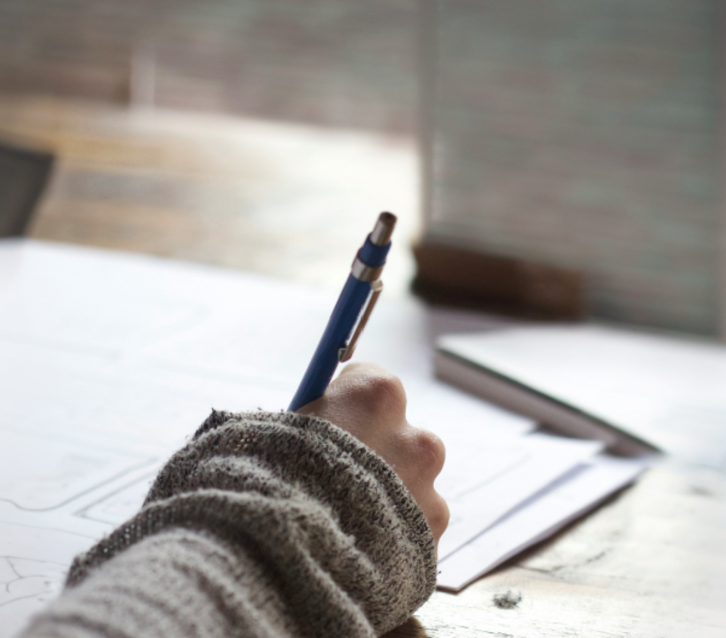 Élève écrivant au stylo sur une feuille d'exercices
